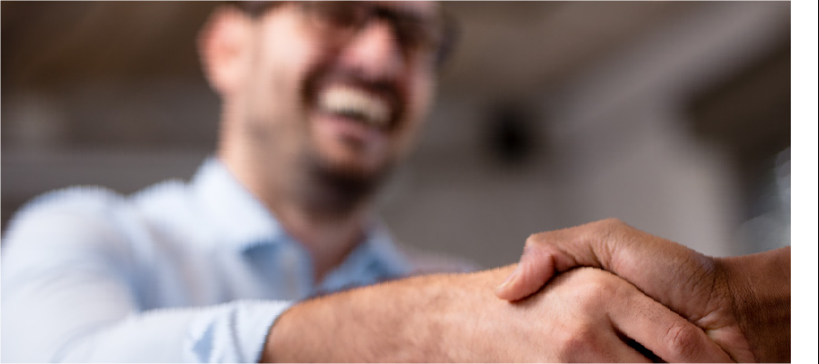 Man smiling and shaking an outstretched hand